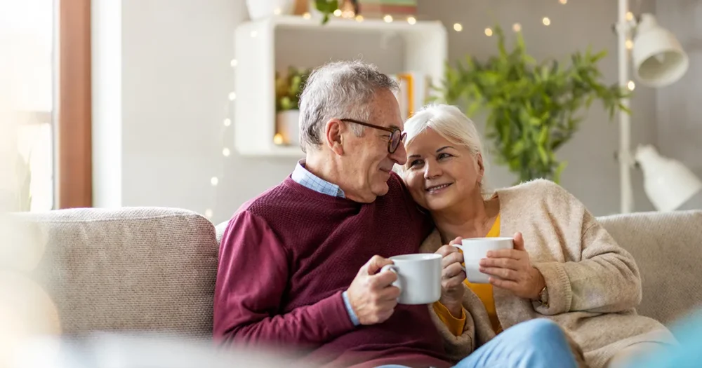 A couple relaxing at home with a cuppa, thinking about how much they need to retire