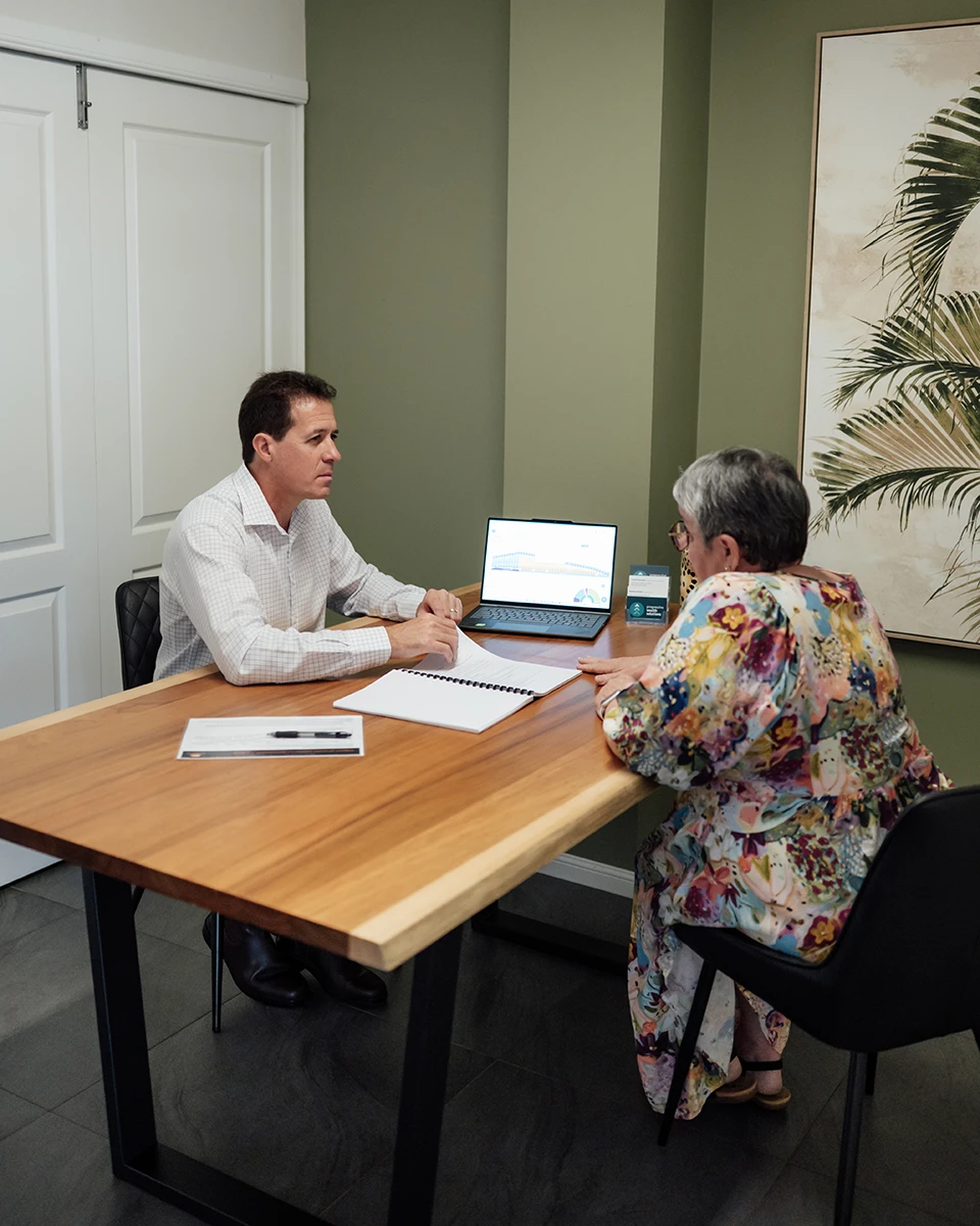 Financial adviser reviewing a retirement plan on a laptop with an older client